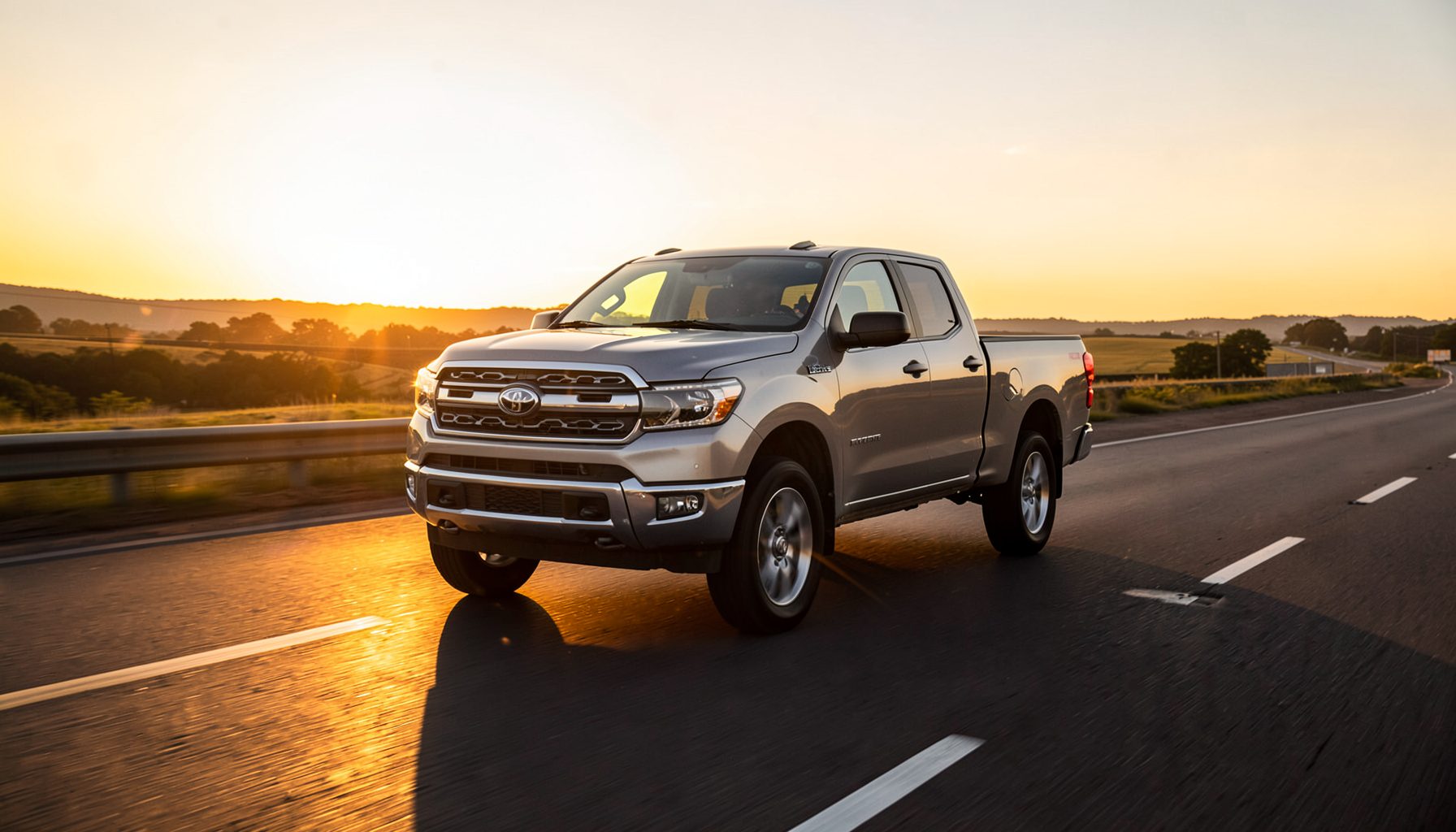A sleek pickup truck driving on an open highway at sunset, warm golden light reflecting off the road, conveying freedom